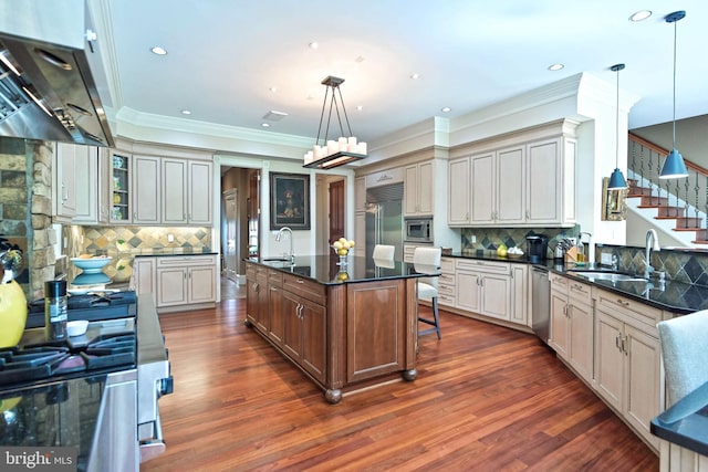 kitchen featuring exhaust hood, a center island with sink, hanging light fixtures, and built in appliances