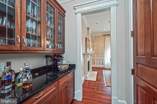 bar featuring dark hardwood / wood-style floors, crown molding, and dark stone countertops