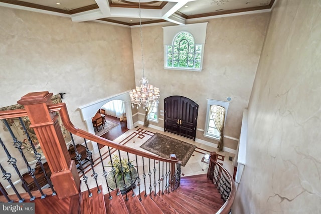 foyer with hardwood / wood-style floors, a high ceiling, coffered ceiling, ornamental molding, and beam ceiling