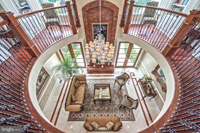 interior space featuring a notable chandelier, light tile patterned flooring, a towering ceiling, and french doors