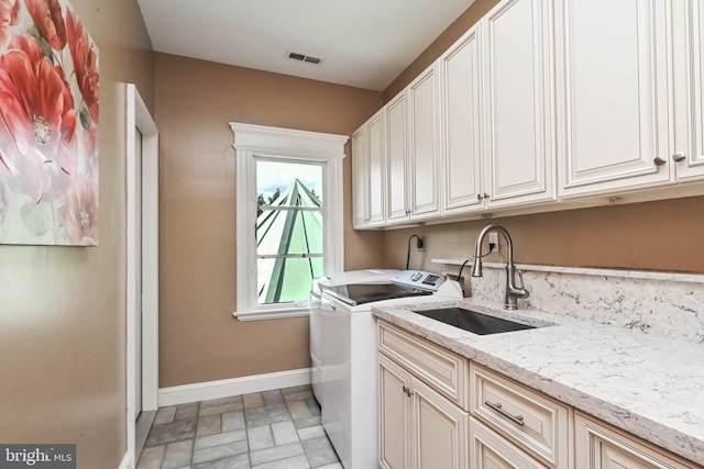 clothes washing area featuring cabinets, independent washer and dryer, and sink