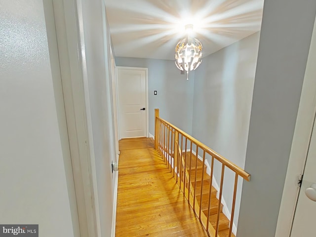 hall with light wood-type flooring and a chandelier