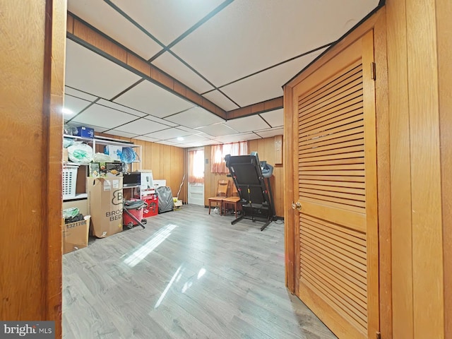 office space with a drop ceiling, light hardwood / wood-style flooring, and wood walls