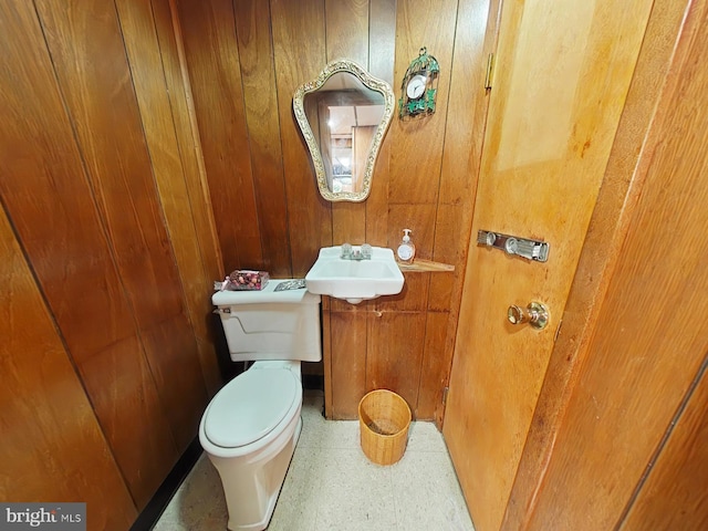 bathroom featuring wood walls, sink, and toilet