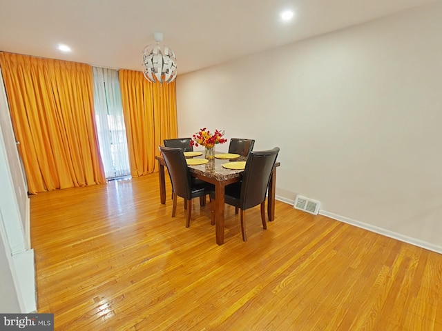 dining space featuring light wood-type flooring and an inviting chandelier