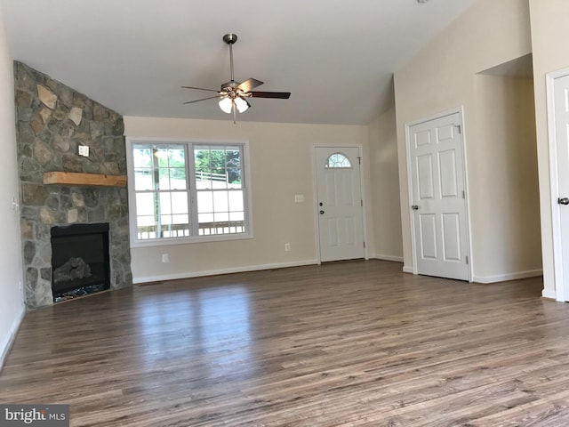 unfurnished living room featuring a stone fireplace, ceiling fan, lofted ceiling, and dark hardwood / wood-style floors