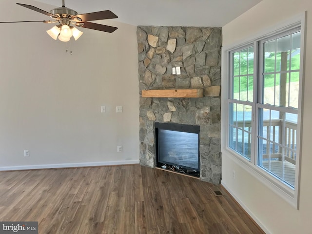 unfurnished living room featuring a stone fireplace, wood-type flooring, and ceiling fan