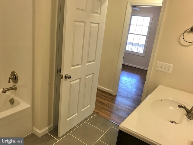 bathroom with washtub / shower combination, vanity, and hardwood / wood-style flooring