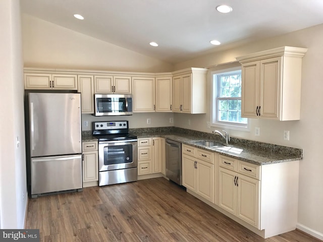 kitchen featuring stainless steel appliances, dark stone counters, dark hardwood / wood-style flooring, sink, and lofted ceiling