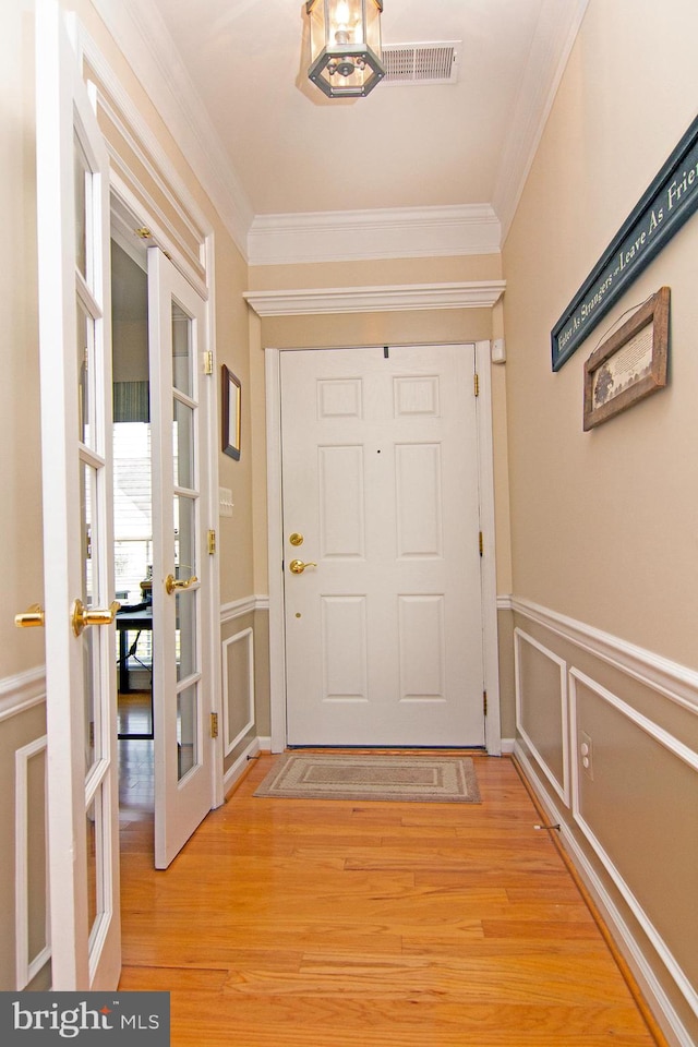 doorway featuring ornamental molding, french doors, and light hardwood / wood-style floors