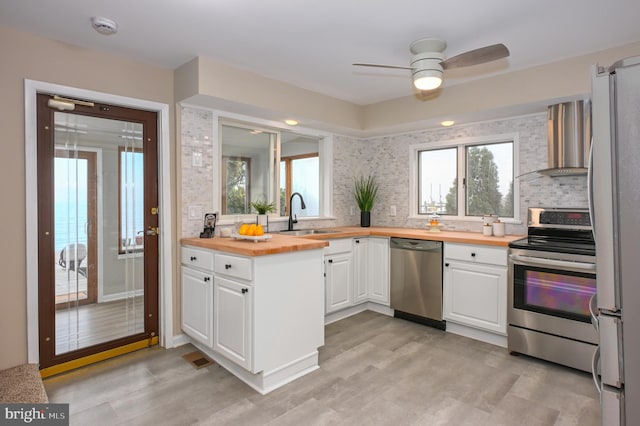 2142 Lake Dr, Pasadena, MD 21122 - kitchen with appliances with stainless steel finishes, wood counters, a sink, wall chimney range hood, and white cabinetry