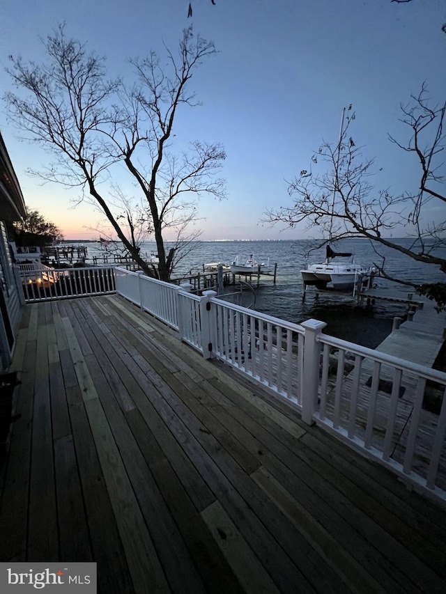 deck at dusk with a dock and a water view