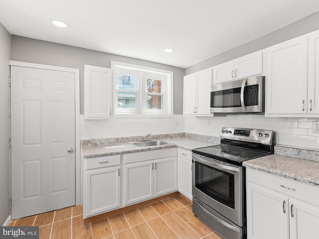 kitchen with white cabinets, stainless steel appliances, sink, and tasteful backsplash