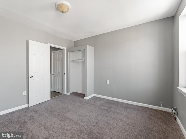 unfurnished bedroom with a closet and dark colored carpet