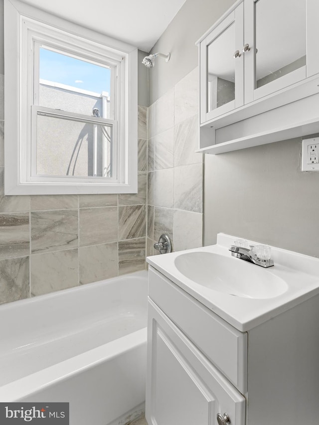 bathroom with tile walls, vanity, and shower / tub combination