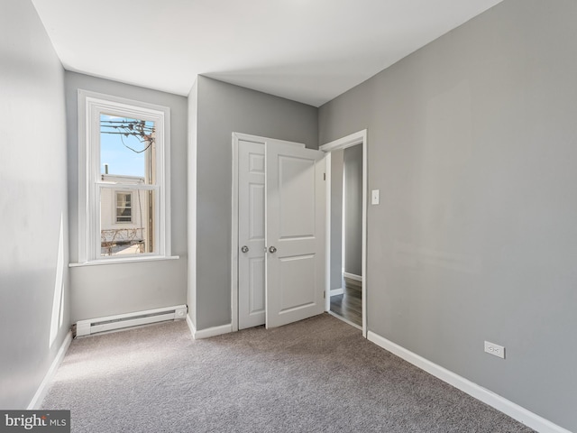 unfurnished bedroom with a baseboard heating unit, carpet floors, a notable chandelier, and a closet