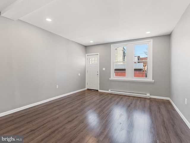 unfurnished room featuring baseboard heating and dark wood-type flooring