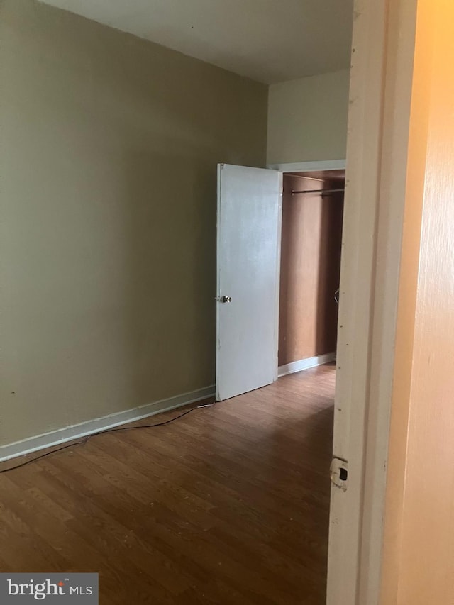 unfurnished bedroom featuring dark wood-type flooring and a closet