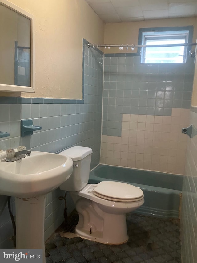 bathroom with tile walls, tiled shower / bath, and toilet