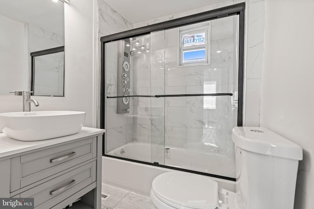 full bathroom with vanity, bath / shower combo with glass door, and toilet