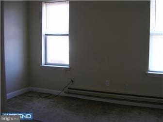 unfurnished room featuring a healthy amount of sunlight and a baseboard heating unit