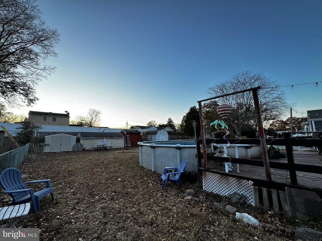 yard at dusk featuring a storage unit and a fenced in pool