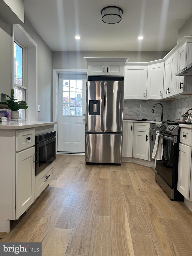 kitchen with white cabinets, stainless steel appliances, and light hardwood / wood-style flooring