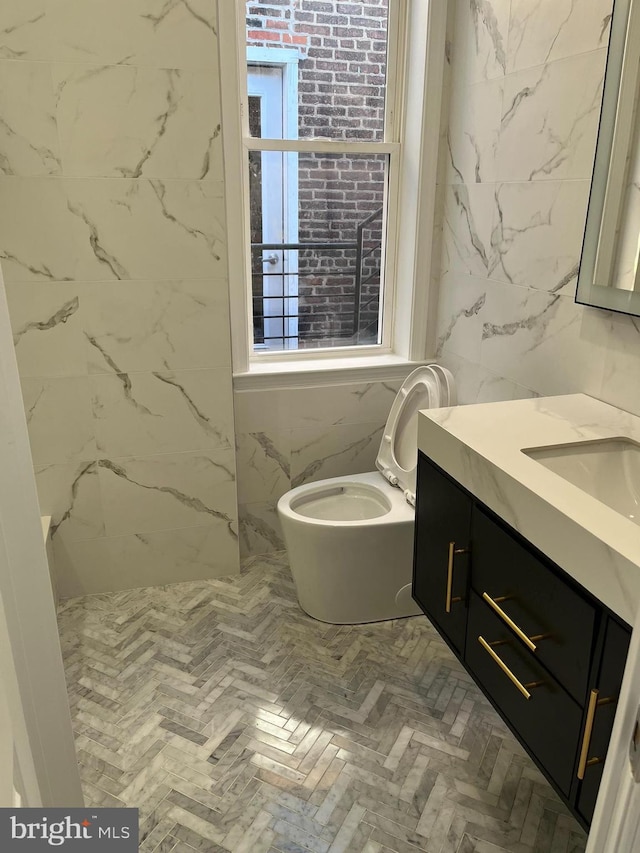 bathroom featuring vanity, toilet, and tile walls