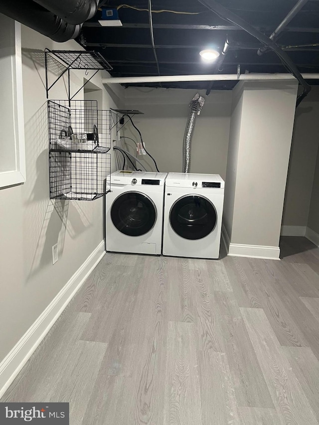 clothes washing area featuring washing machine and clothes dryer and light hardwood / wood-style flooring