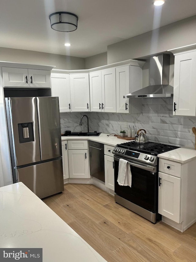 kitchen featuring white cabinets, wall chimney exhaust hood, and stainless steel appliances