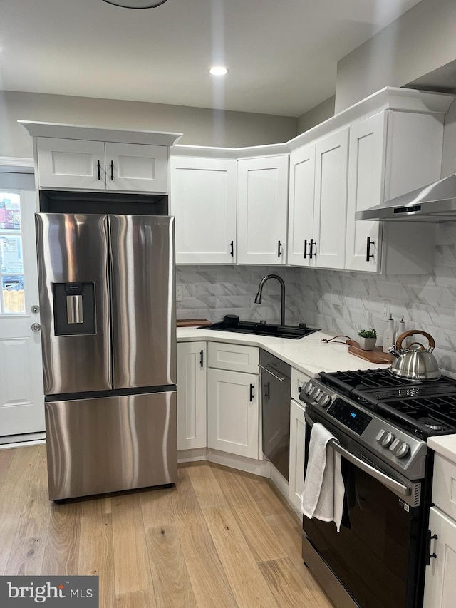 kitchen with white cabinets, light wood-type flooring, sink, and appliances with stainless steel finishes