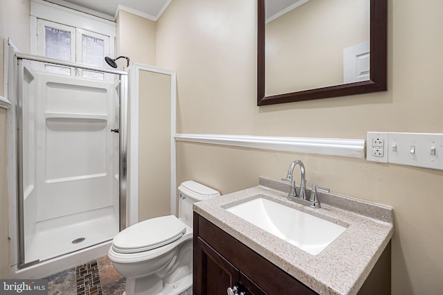 bathroom featuring vanity, toilet, a shower with shower door, and crown molding