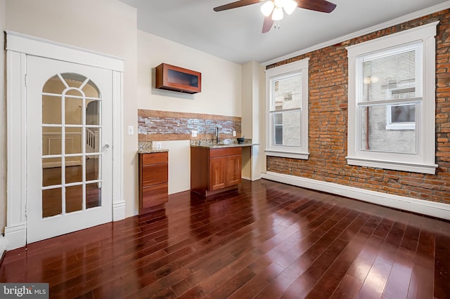 bar with light stone countertops, ceiling fan, dark wood-type flooring, brick wall, and decorative backsplash