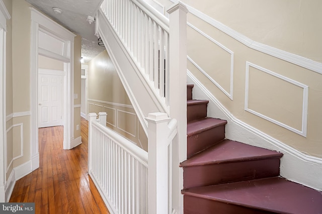 stairs featuring a textured ceiling and hardwood / wood-style flooring