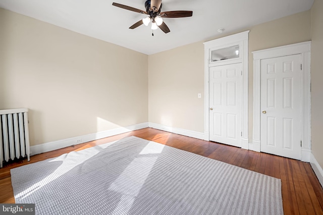 unfurnished bedroom with radiator heating unit, dark hardwood / wood-style flooring, and ceiling fan