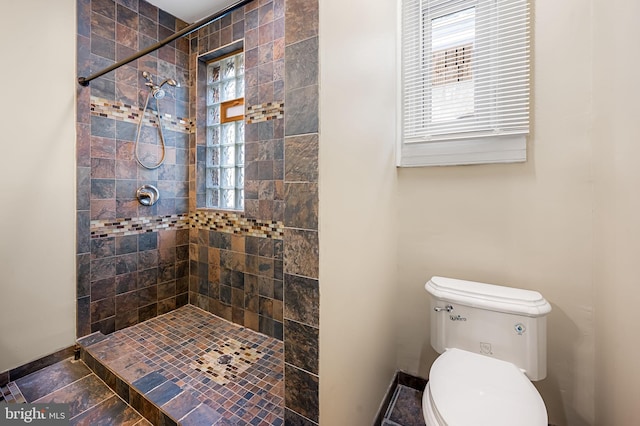 bathroom featuring a tile shower and toilet