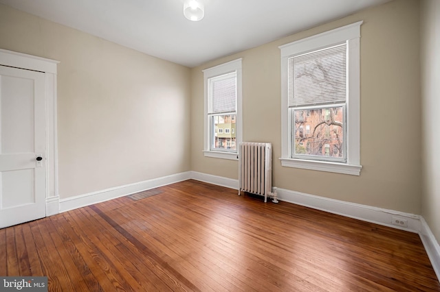 unfurnished room with radiator heating unit and wood-type flooring