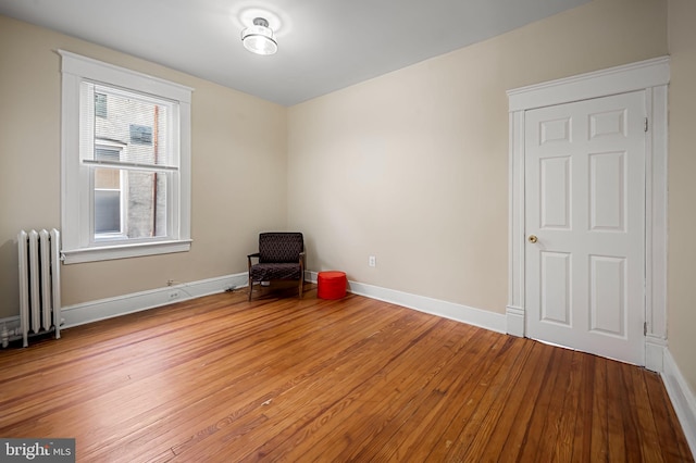 empty room featuring radiator and hardwood / wood-style floors