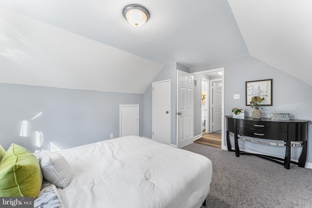 bedroom featuring lofted ceiling and dark carpet