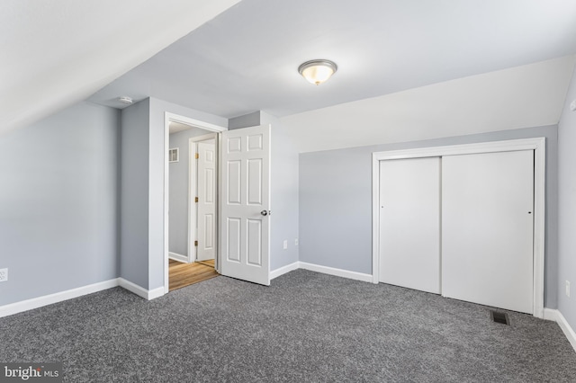 additional living space with dark colored carpet and vaulted ceiling