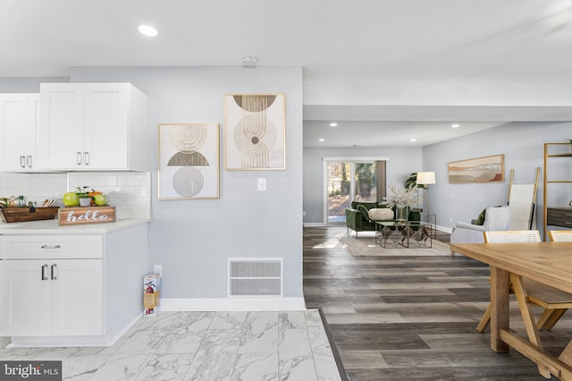 kitchen with backsplash, wood-type flooring, and white cabinets