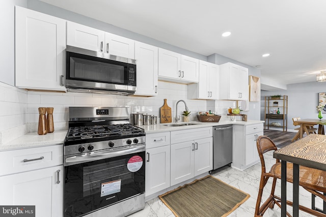 kitchen featuring white cabinetry, stainless steel appliances, sink, and backsplash