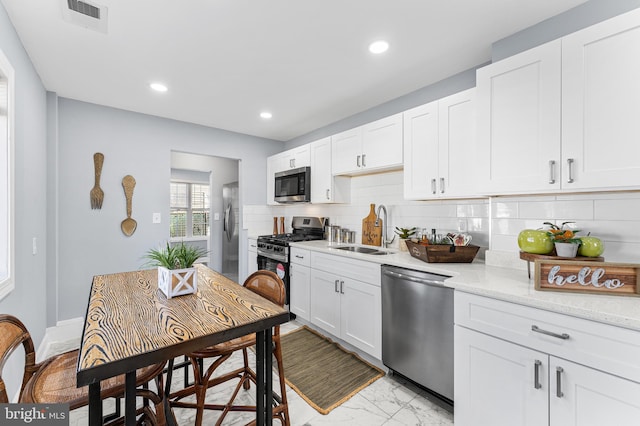 kitchen with backsplash, appliances with stainless steel finishes, sink, and white cabinets