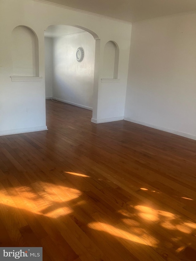 empty room with dark wood-type flooring and crown molding