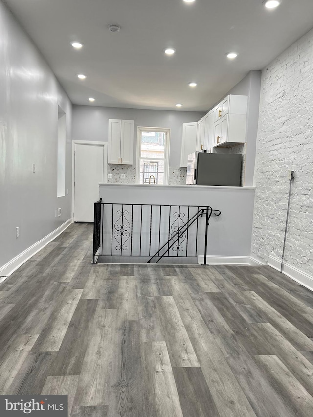 kitchen with hardwood / wood-style flooring, white cabinetry, sink, stainless steel fridge, and decorative backsplash