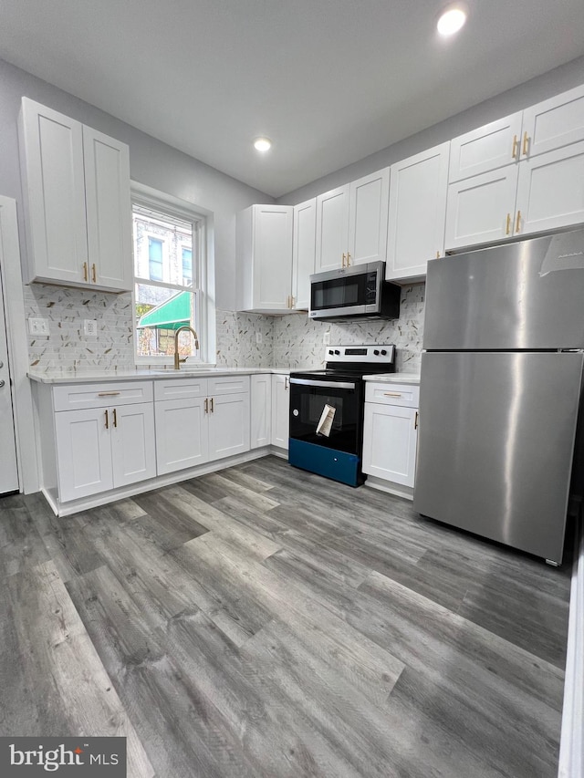 kitchen featuring stainless steel appliances, white cabinetry, light wood-type flooring, and backsplash