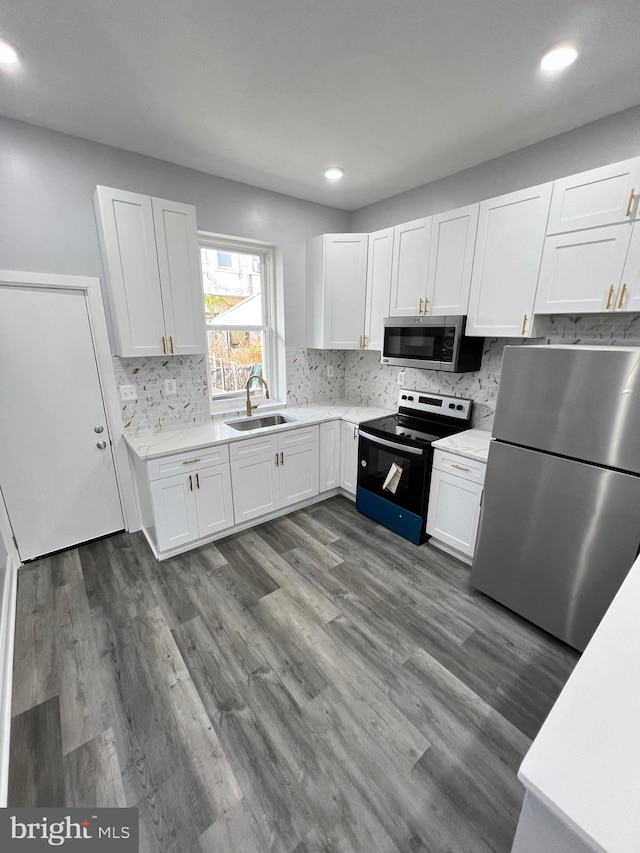 kitchen featuring stainless steel appliances, dark hardwood / wood-style flooring, white cabinets, sink, and backsplash