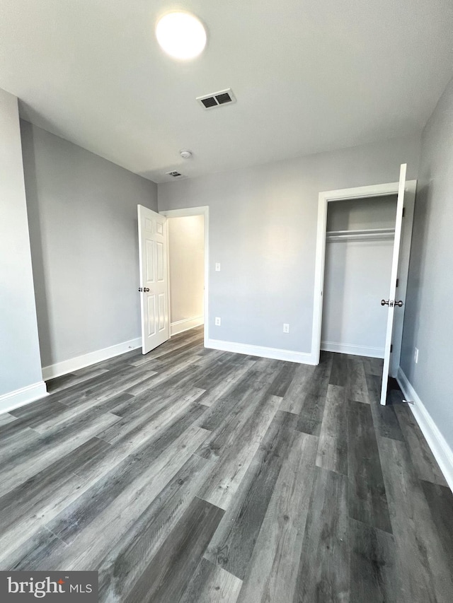 unfurnished bedroom with dark hardwood / wood-style floors and a closet