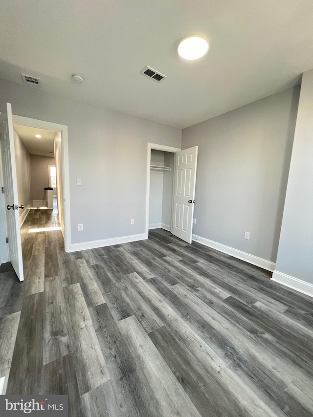 unfurnished bedroom with a closet and dark hardwood / wood-style flooring