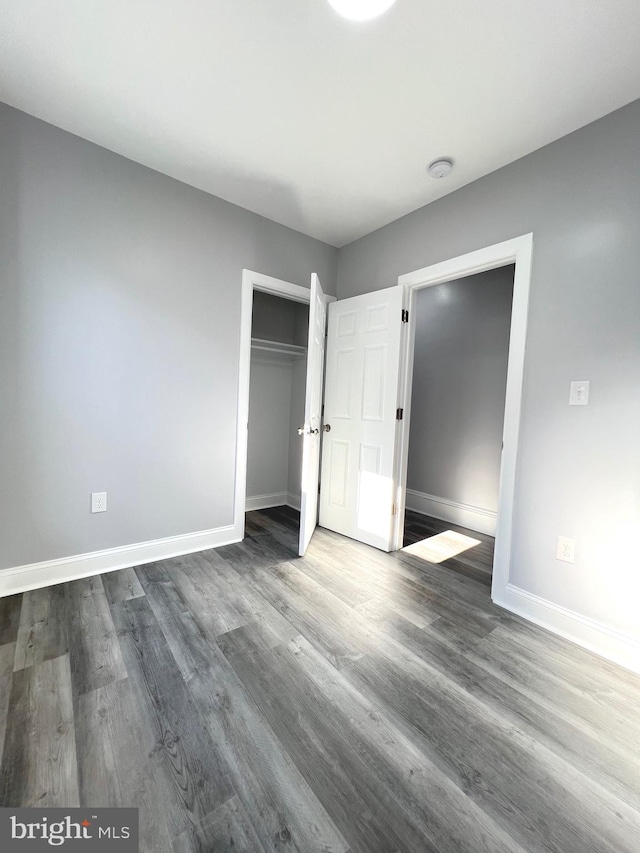 unfurnished bedroom featuring dark wood-type flooring and a closet